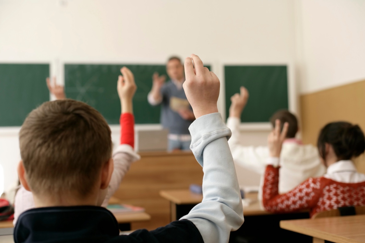 Alumnos levantando la mano, participando en clase