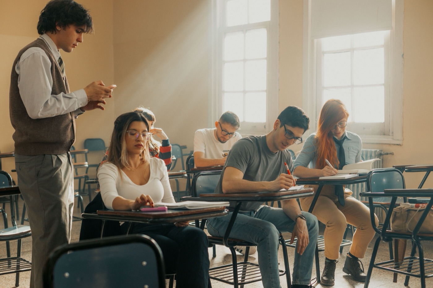Docente revisando el celular mientras los alumnos trabajan